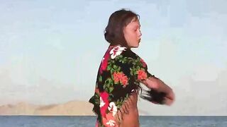 A member shows a girl the secrets of naked sunbathing on the beach