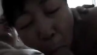 An adult Chinese woman practices her blowjob skills on a man’s dick