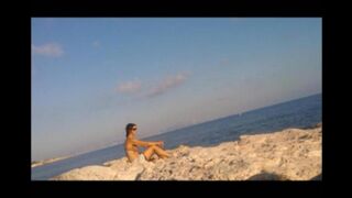 A young girl sunbathes naked on the beach. It's very dangerous